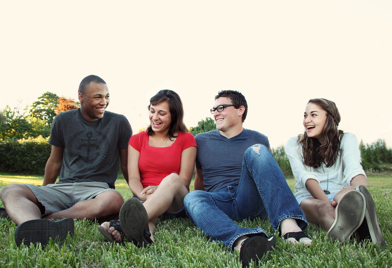 Group of people smiling while sitting on grass